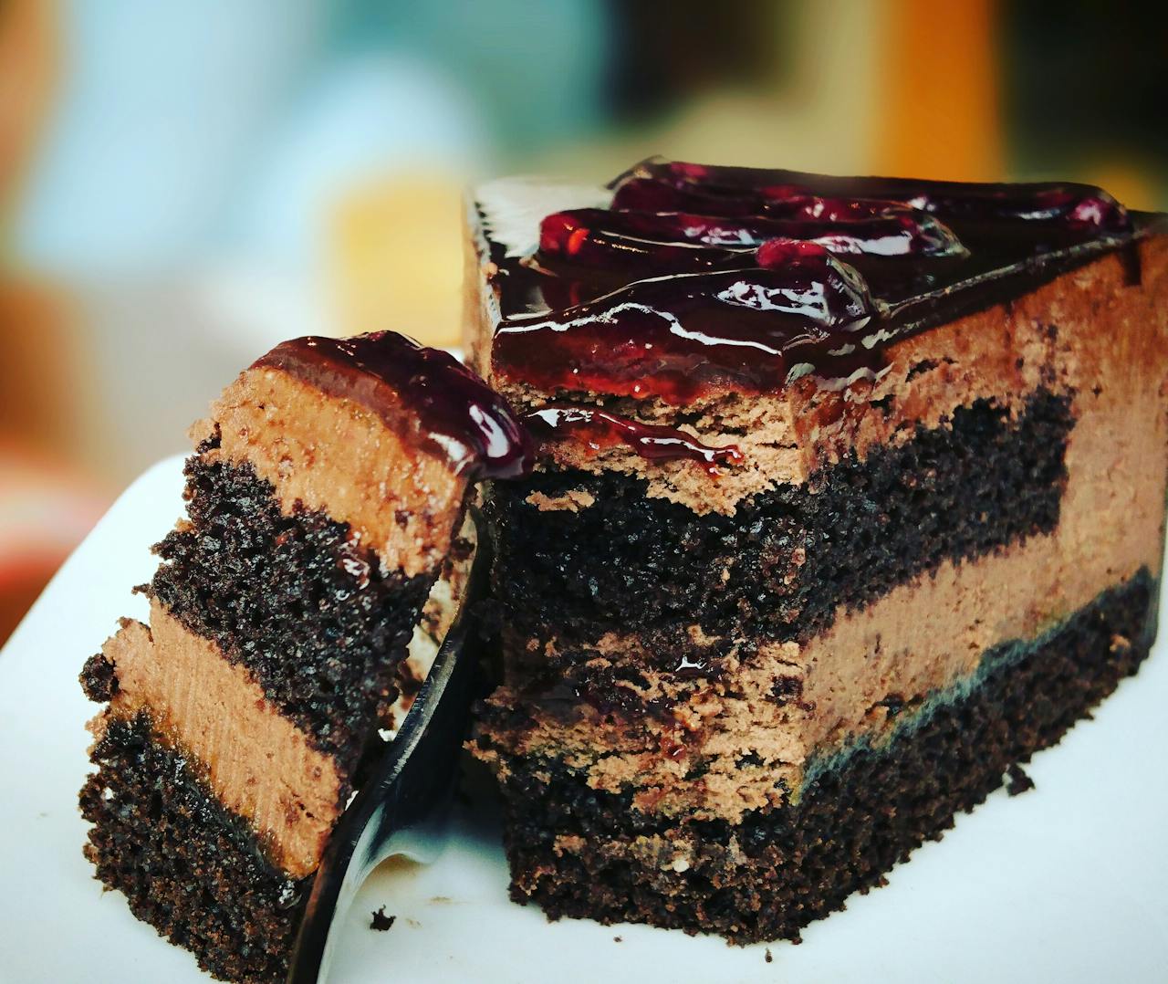 Close-up of a rich chocolate cake slice with blueberry topping, perfect for dessert lovers.